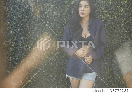 A beautiful lady is holding her shirt while standing outside. 33779287