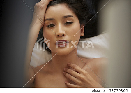 A beautiful young woman is relaxing while posing on the bed. 33779306