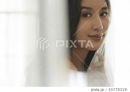 photo of a woman holding a curtain and looking at camera. photo of a woman holding a curtain and looking at camera. 33779319
