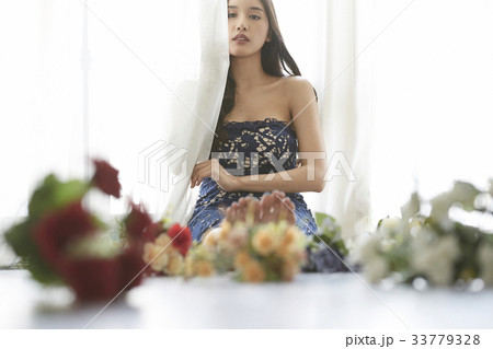 photo of a woman sitting on floor and holding a curtain. 33779328