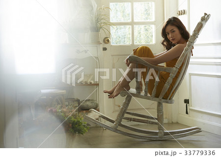 photo of a woman sitting on a rocking chair and looking at camera. 33779336