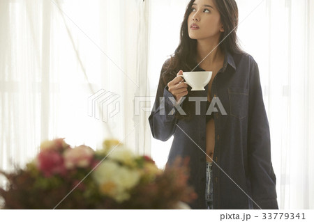 Asian beautiful woman holding a cup of morning cofee in her room 33779341