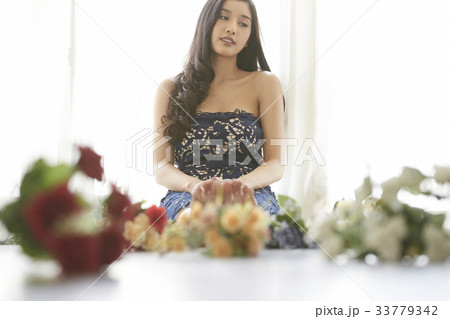 photo of a woman sitting on floor with flowers in front of her. 33779342