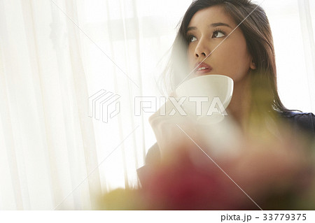 photo of a beautiful woman holding a cup and looking up. 33779375