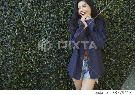 portrait of a girl standing outside and smiling with her hands on her chin 33779418