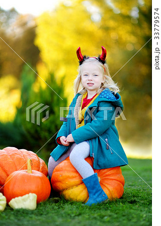Adorable little girl wearing halloween costume having fun on a pumpkin patch 33779574