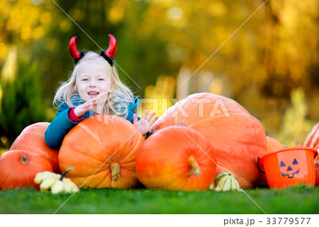 Adorable little girl wearing halloween costume having fun on a pumpkin patch 33779577