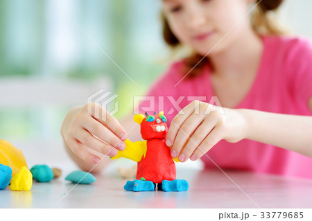 Cute little girl having fun with colorful modeling clay at a daycare Cute little girl having fun with colorful modeling clay at a daycare 33779685