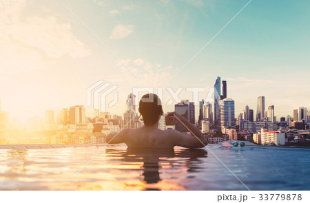 a man relax in swimming pool in sunrise, in city a man relax in swimming pool in sunrise, in city 33779878