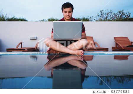 a man working on laptop computer, at pool 33779882