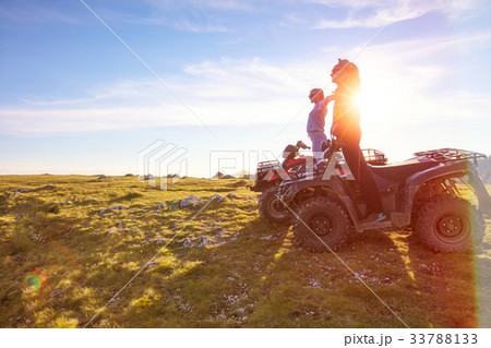 Rear view of young pair near atv. Man is showing Rear view of young pair near atv. Man is showing 33788133