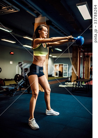 Attractive female athlete performing a kettle-bell 33788264