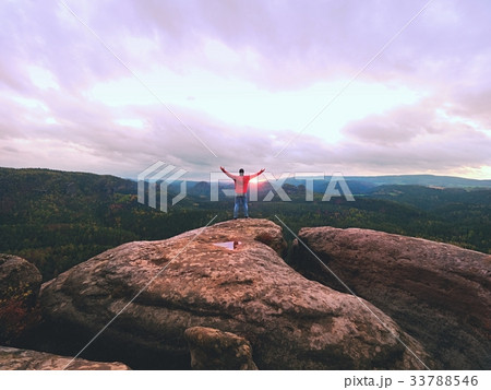 Man hiker on sharp cliff. Hiker climbed up to peak Man hiker on sharp cliff. Hiker climbed up to peak 33788546