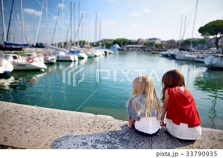 Two cute little sisters watching small yachts in harbor in Desenzano del Garda  33790935