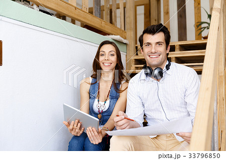 Portrait of two young people sitting at the stairs in office 33796850