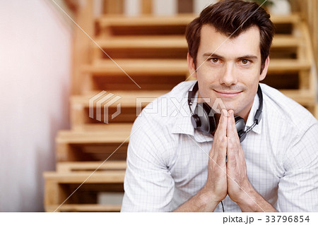 Portrait of young man sitting at the stairs in office 33796854