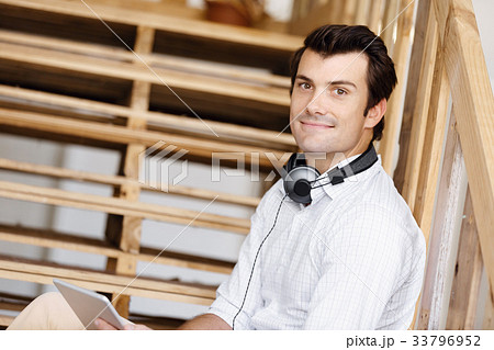 Portrait of young man sitting at the stairs in office 33796952