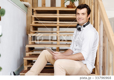 Portrait of young man sitting at the stairs in office Portrait of young man sitting at the stairs in office 33796968