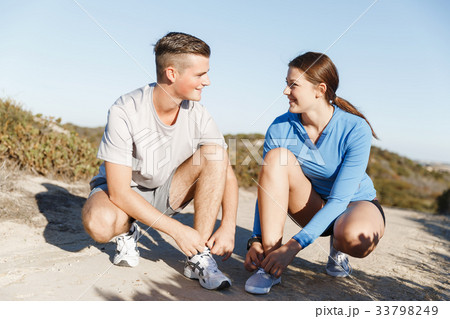 Couple of runners lace their shoes and prepare to jogging 33798249