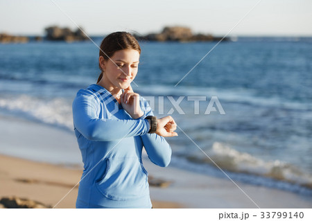Runner woman with heart rate monitor running on beach Runner woman with heart rate monitor running on beach 33799140