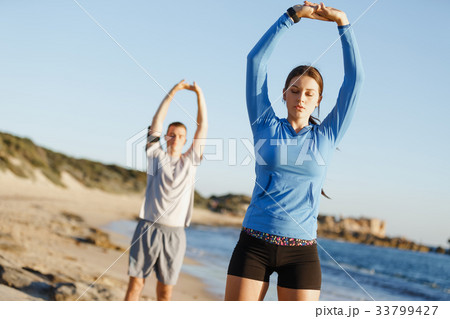Young couple on beach training together Young couple on beach training together 33799427