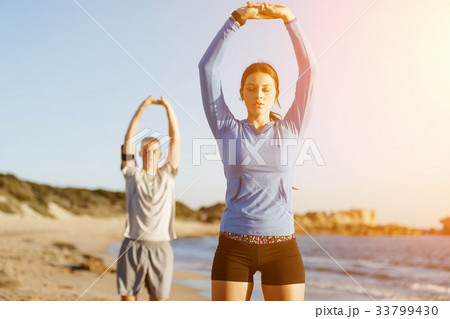 Young couple on beach training together Young couple on beach training together 33799430