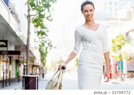 Business woman pulling suitcase bag walking in city Business woman pulling suitcase bag walking in city 33799772