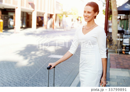 Business woman pulling suitcase bag walking in city Business woman pulling suitcase bag walking in city 33799891