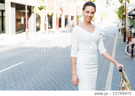 Business woman pulling suitcase bag walking in city 33799972