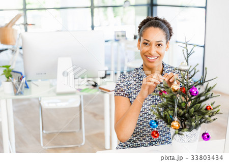 Portrait of smiling afro-american office worker decorating christmas tree in offfice 33803434