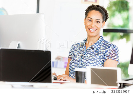 Portrait of smiling afro-american office worker sitting in offfice 33803907