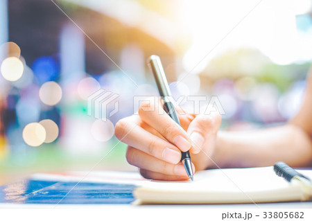 Woman's hand writing on a notepad with a pen Woman's hand writing on a notepad with a pen 33805682