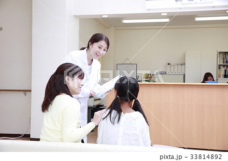 待合室で女医に声をかけられる女の子と母親 待合室で女医に声をかけられる女の子と母親 33814892