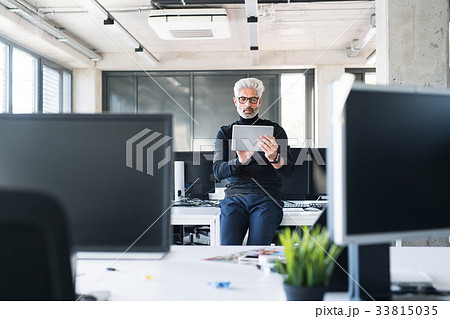 Mature businessman with tablet in the office. Mature businessman with tablet in the office. 33815035