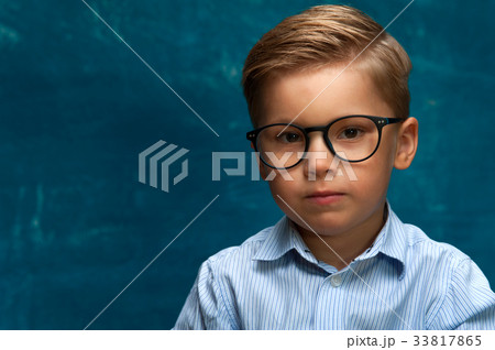 Pensive boy wearing eyeglasses on blue backdrop Pensive boy wearing eyeglasses on blue backdrop 33817865