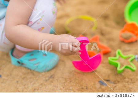 Kid hand playing with plastic toy in sand box 33818377
