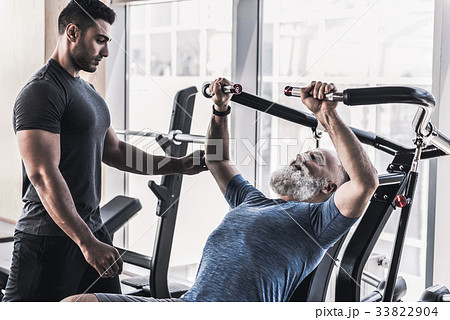 Concentrated old male is having workout with his Concentrated old male is having workout with his 33822904