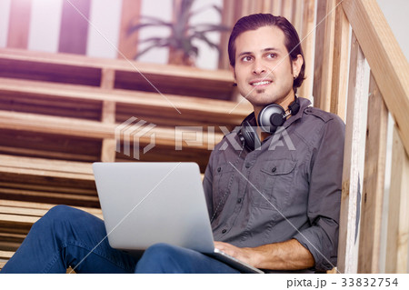 Portrait of young man sitting at the stairs in office 33832754