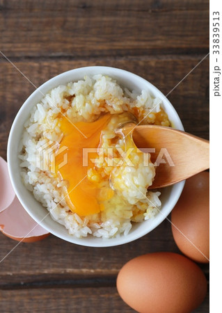 醤油をかけて黄身を崩した卵かけご飯と茶色の生卵 33839513