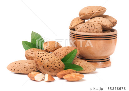 Almonds in a wooden bowl with leaves isolated on Almonds in a wooden bowl with leaves isolated on 33858678