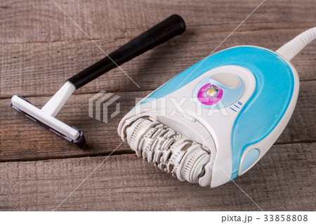electric epilator with razor on a light wooden 33858808