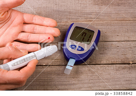 blood glucose meter with a hand on an old wooden 33858842