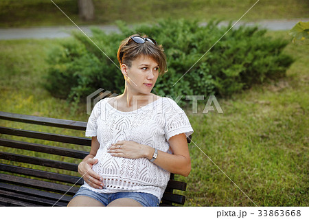 Pregnant girl sitting on bench 33863668