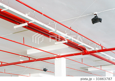Fire sprinkler with red pipes hanging the ceiling  33863787