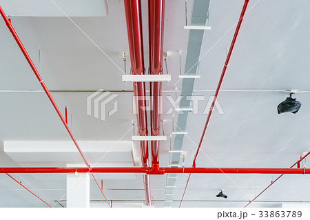 Fire sprinkler with red pipes hanging the ceiling  33863789