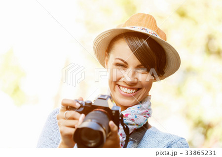 Outdoor summer smiling lifestyle portrait of pretty young woman with camera 33865231