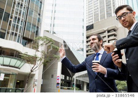 Two young businessmen hailing for a taxi Two young businessmen hailing for a taxi 33865546