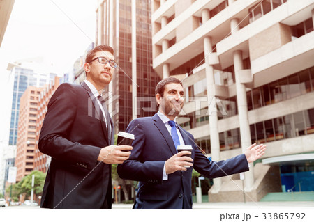 Two young businessmen hailing for a taxi Two young businessmen hailing for a taxi 33865792