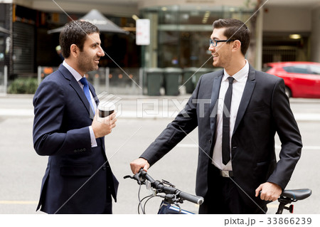 Two young businessmen with a bike in city centre Two young businessmen with a bike in city centre 33866239
