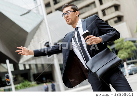 Young businessmen hailing for a taxi Young businessmen hailing for a taxi 33868011